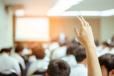 Conférences Businessman raising hand during seminar. Businessman Raising Hand at a Conference an